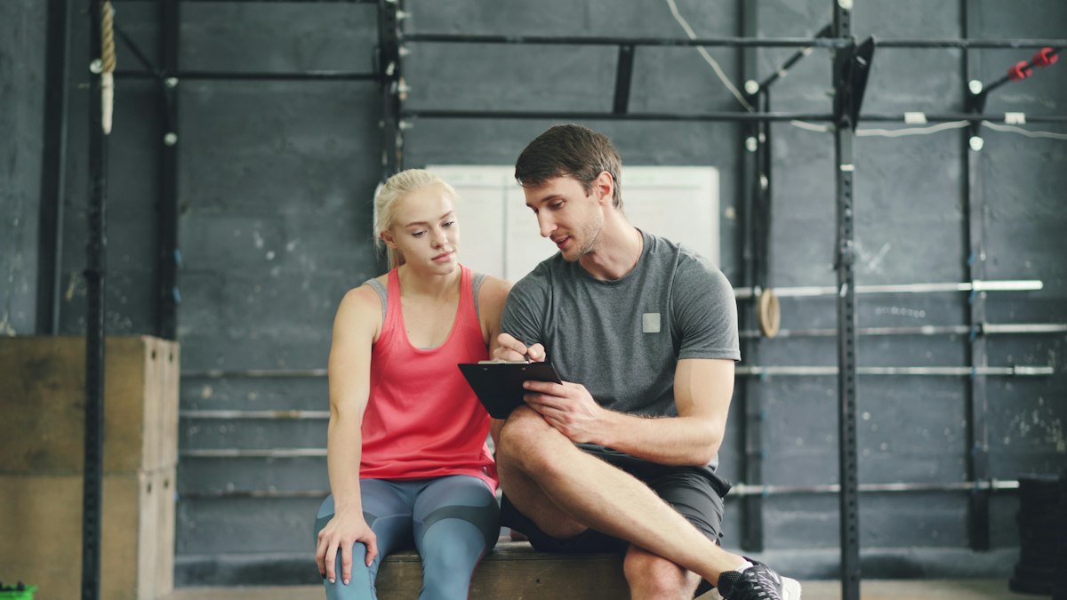 Coach reviewing a training plan one-on-one with a client in the gym